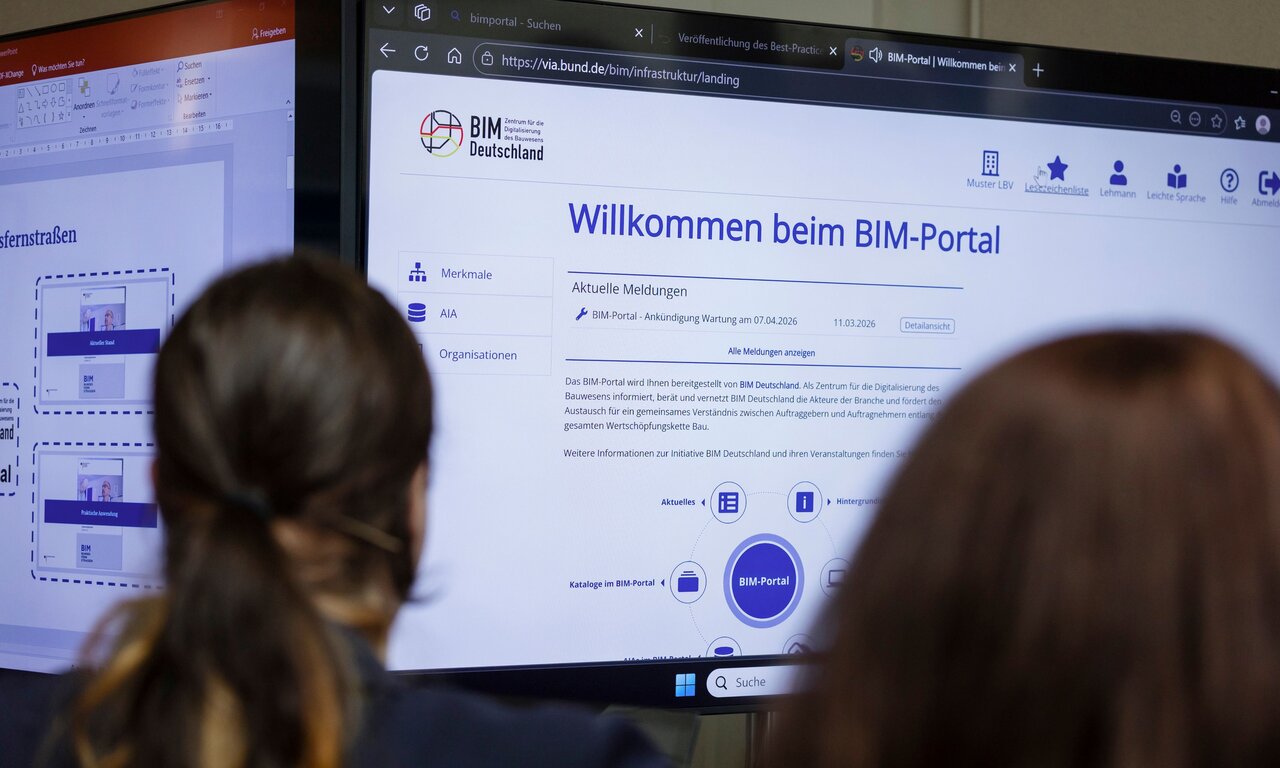 Zwei Teilnehmerinnen des Dialogforums Bundesfernstraßen Digital im März 2026 blicken an einer Themeninsel auf einen Bildschirm, der die Startseite des BIM-Portals zeigt.